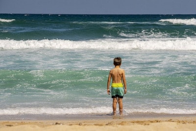 Kind am Strand mit starken Wellen und Strömung